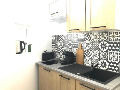- une cuisine avec un évier et du carrelage noir et blanc dans l'établissement LE PETIT PRESBYTERE - HyperCentre - Rez de Chaussée - Thermes, à Vichy