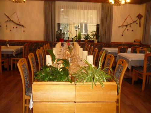 una sala da pranzo con un lungo tavolo con piante di Gasthof-Fleischerei Engl a Kötschach-Mauthen
