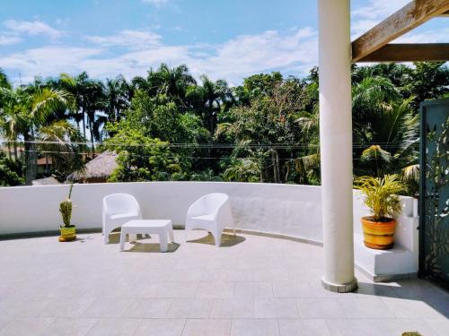 a patio with white chairs and a fence at Okaina Studio Rooftop in Cabarete