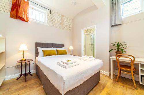 ロンドンにあるLotus GuestHouseのベッドルーム1室(ベッド1台、テーブル、椅子付)
