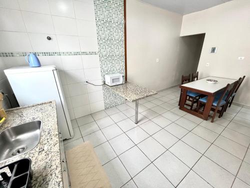 a kitchen with a sink and a table and a refrigerator at Casa Ampla - Ótima Localização in Piracicaba