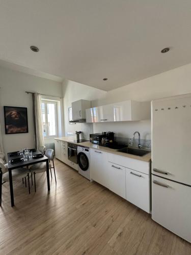 uma cozinha com armários brancos, uma mesa e um frigorífico em The Loft, Marseille 8 ème em Marselha