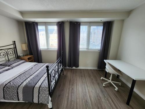 um quarto com uma cama, uma secretária e janelas em Scarborough Townhouse em Toronto