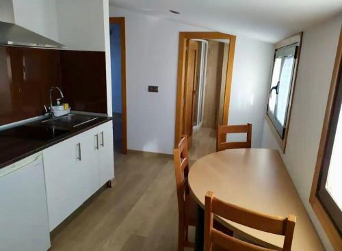 a kitchen with a wooden table and a kitchen with a sink at Atico Praia Cambados in Cambados