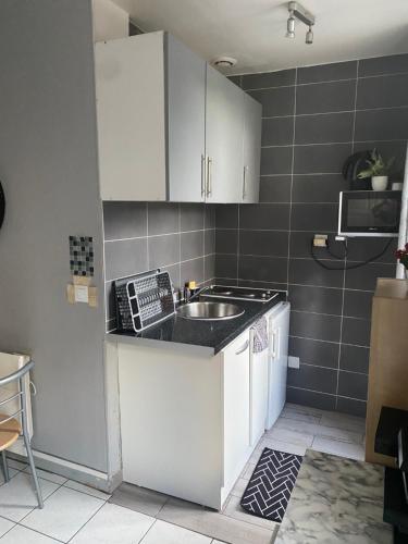 une cuisine avec des armoires blanches et un évier dans l'établissement Studio charmant centre d Aubervilliers, à Aubervilliers