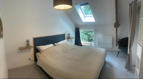 um quarto com uma grande cama branca e uma clarabóia em Maison cosy avec extérieur et piscine partagée em Mespaul
