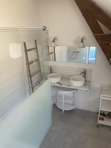 uma casa de banho com 2 lavatórios e um espelho em Maison cosy avec extérieur et piscine partagée em Mespaul