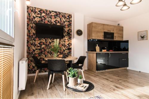 ein Wohnzimmer mit Tisch und Stühlen und eine Küche in der Unterkunft Tucan - 77 Apartments Wigury - Dostęp na KOD - Parking - Smaczna Kawa - Centrum - Blisko Piotrkowska - Galeria - Widok na miasto - Klimatyzacja - 7 piętro - FV in Łódź