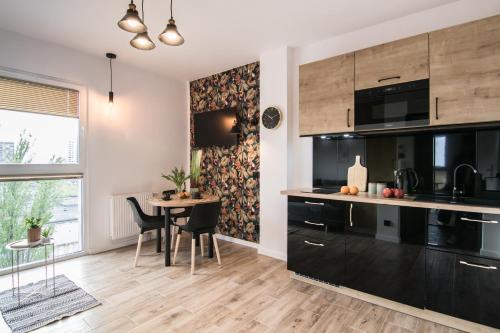 eine Küche mit schwarzen Geräten und einem Tisch mit Stühlen in der Unterkunft Tucan - 77 Apartments Wigury - Dostęp na KOD - Parking - Smaczna Kawa - Centrum - Blisko Piotrkowska - Galeria - Widok na miasto - Klimatyzacja - 7 piętro - FV in Łódź