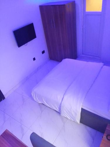 1 dormitorio con 1 cama y TV en la pared en Ge-Mart Hotels and Suites, en Lagos