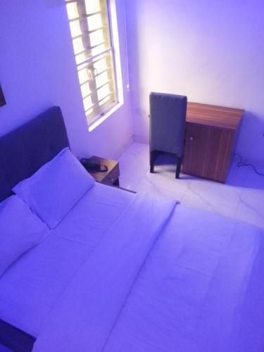 um quarto com uma cama, uma cadeira e uma janela em Ge-Mart Hotels and Suites em Lagos