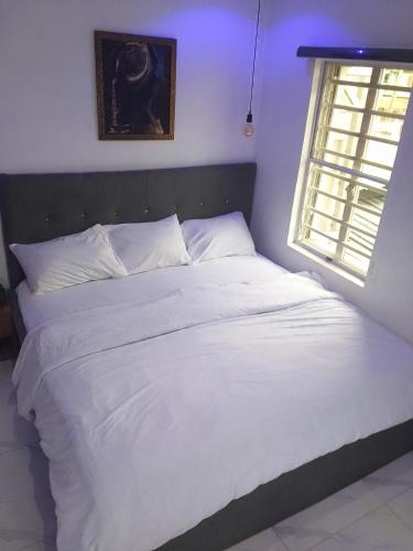duże białe łóżko w sypialni z oknem w obiekcie Ge-Mart Hotels and Suites w mieście Lagos