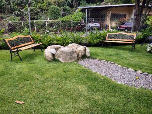 Los NaranjosにあるOrange Countryの芝生と岩の庭のベンチ2つ