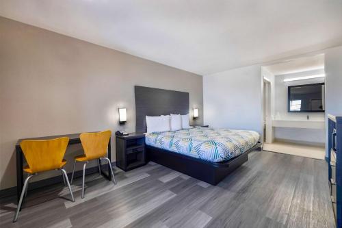 ein Hotelzimmer mit einem Bett, einem Schreibtisch und Stühlen in der Unterkunft Motel 6 Lake Charles, LA in Lake Charles