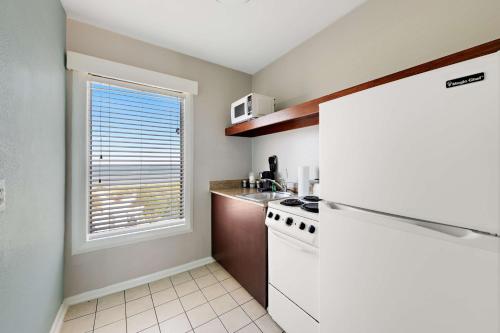 a kitchen with a white refrigerator and a window at Best Western Plus Holiday Sands Inn & Suites in Norfolk