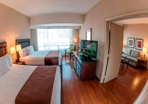 a hotel room with two beds and a flat screen tv at Clarion Suites Guatemala City in Guatemala