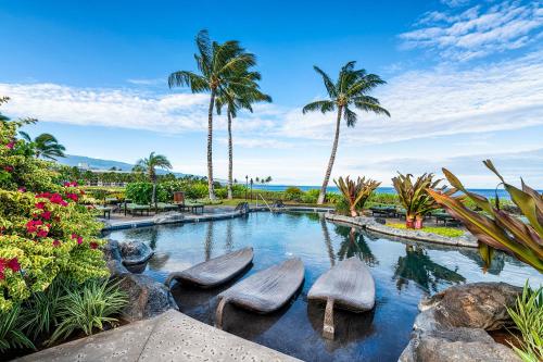 una piscina con 3 sillas y palmeras en Halii Kai 11D, en Waikoloa