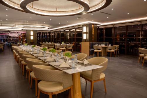 Best Western Plus Danat Almansak Hotel في أبها: غرفة طعام مع طاولة وكراسي طويلة