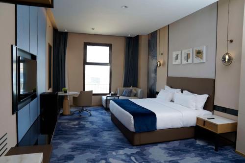 a hotel room with a bed and a television at Best Western Plus Danat Almansak Hotel in Abha