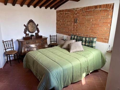 een slaapkamer met een groen bed en een bakstenen muur bij La casa nel borgo in Cavriglia