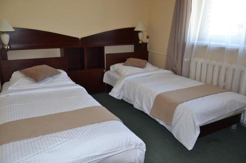 two beds in a hotel room next to a window at Hotel Solpark in Kleszczów
