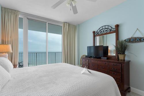 a bedroom with a bed and a tv and a window at Lighthouse By Liquid Life in Gulf Shores