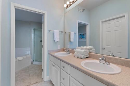 La salle de bains est pourvue de 2 lavabos et d'un grand miroir. dans l'établissement Lighthouse By Liquid Life, à Gulf Shores