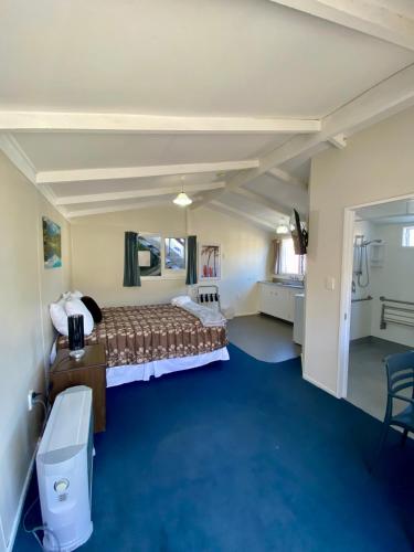 a hotel room with a bed and a blue carpet at Sea View Motel - Unit 5 in Kaikoura