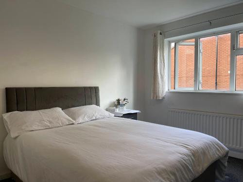 een slaapkamer met een groot wit bed en een raam bij Homestays-Close to Coventry City and University I Free Parking I Wi-Fi in Coventry