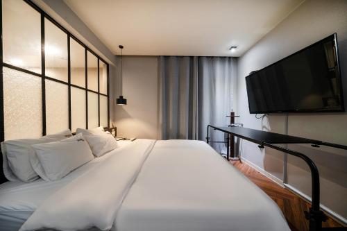 2 Heaven Hotel Songdo في بوسان: غرفة نوم مع سرير أبيض كبير مع تلفزيون بشاشة مسطحة