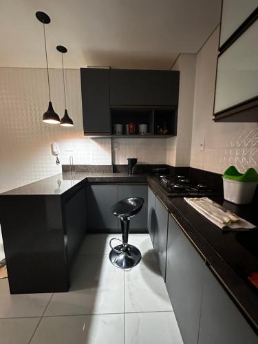 a kitchen with a stove and a stool in it at Apartamento em área nobre in Conselheiro Lafaiete