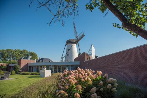 a windmill on top of a building with flowers at Hotel AL Mulino in Maasmechelen