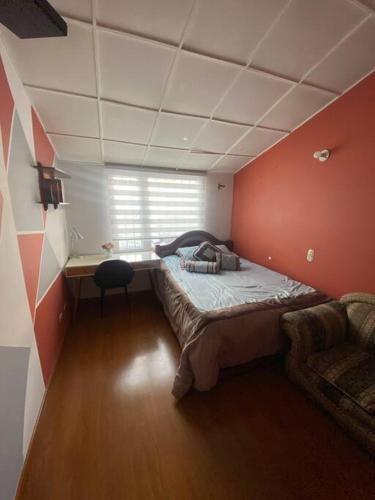 um pequeno quarto com uma cama e uma janela em Hermosa casa con gran ubicación em Bogotá