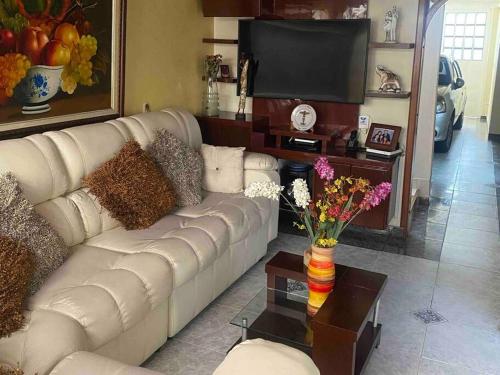 a living room with a white couch and a tv at Hermosa casa con gran ubicación in Bogotá