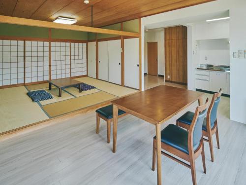 a dining room with a wooden table and chairs at Guest Living Mu Nanki Shirahama in Shirahama