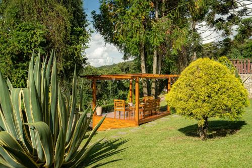 a garden with a wooden gazebo and a bench at Pousada das Pedras in Monte Verde