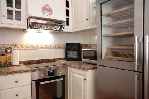 a kitchen with white cabinets and a stainless steel refrigerator at Casa do Vale - Moradia 3 quartos - Rio Minho-Seixas-Caminha - Casa de férias completa com piscina in Caminha
