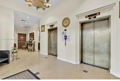 a lobby with a elevator and a clock on a wall at Private bedroom in Miami Coral Gables in Miami