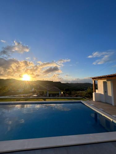 a swimming pool with the sunset in the background at Casinha da Lareira - Quintinha dos Cavalos- Arruda dos Vinhos in Arruda dos Vinhos