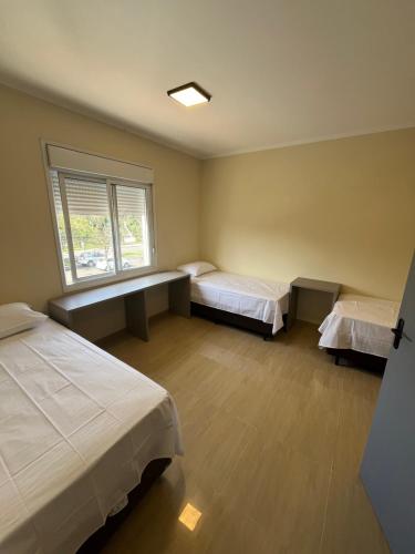 a room with two beds and a window at Astor Hostel in Campinas