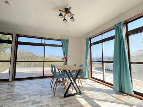 a dining room with a table and chairs and windows at Itoshima Beach House in Itoshima