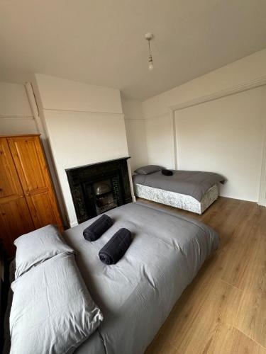 two beds in a room with a fireplace at Very Nice Triple Room at 2 Iveragh Rd-5 in Dublin