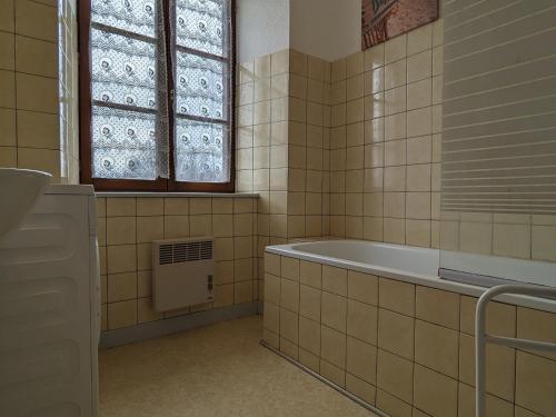 uma casa de banho com uma banheira e uma janela em Gîte Saint-Privat-d'Allier, 5 pièces, 7 personnes - FR-1-582-3 em Saint-Privat-dʼAllier