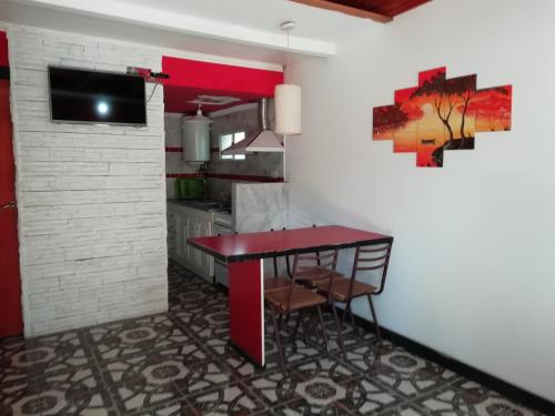 - une cuisine avec une table rouge et des chaises dans l'établissement Cabañas Ezequiel, à Villa Carlos Paz