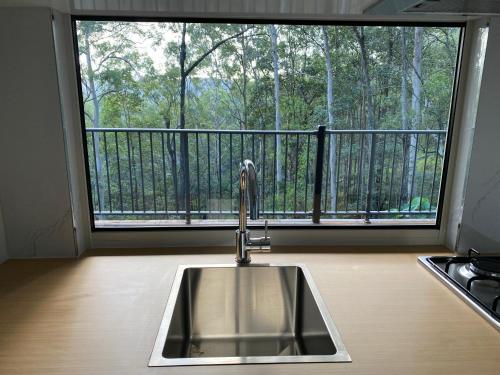 a kitchen sink in front of a large window at 424 Trees Tiny Home in Tallebudgera