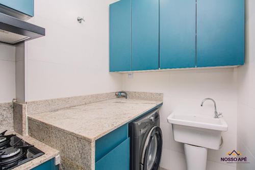 a small kitchen with blue cabinets and a washing machine at Nosso Apê Teixeiras: 2/4 | Garagem | Acessível NA812T in Juiz de Fora