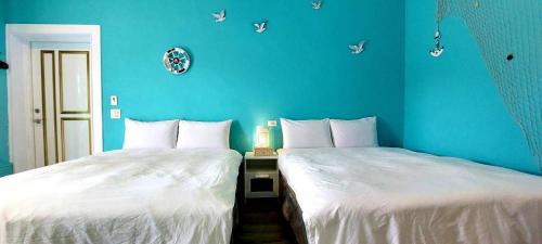 two beds in a room with blue walls at 賞星月木 in Eluan