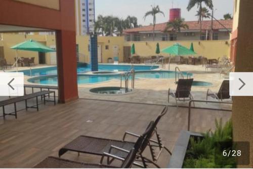 a large swimming pool with chairs and umbrellas at Apartamento Mobiliado com Área de Lazer in Caldas Novas