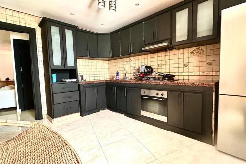 a kitchen with dark green cabinets and appliances at Grand Appartement Agdal Centre I Suite & Billard in Rabat