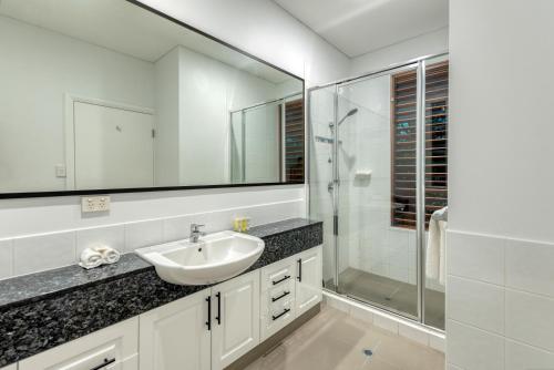 Un baño con lavabo y ducha de cristal. en Villa 3 @ Chez Willow, 2 mins to Four Mile Beach, en Port Douglas